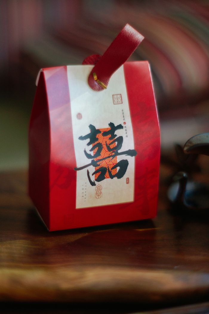 Red Chinese gift box with elegant calligraphy on wooden table, suitable for festive themes.
